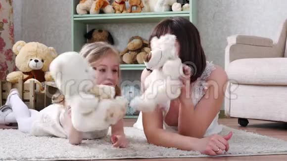 母亲和女儿躺在地板上玩着她柔软的玩具视频的预览图