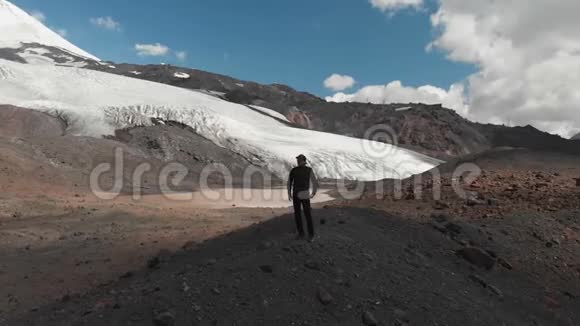 一个戴着帽子戴着墨镜站在悬崖上被白雪覆盖的高加索山脉包围着的人周围视频的预览图