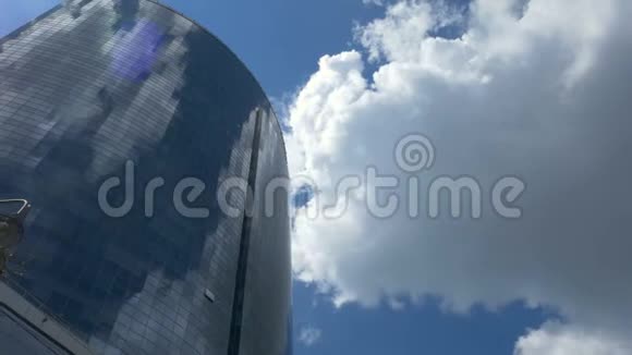 从下面的一个大玻璃商务中心在背景是移动的灰色云在玻璃里反射视频的预览图