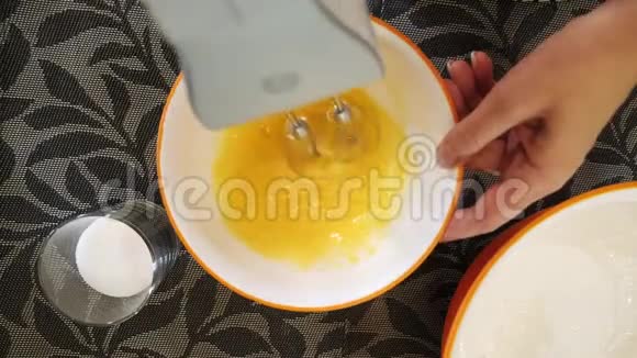 用电动搅拌器在碗中搅拌蛋黄的顶部视图视频的预览图