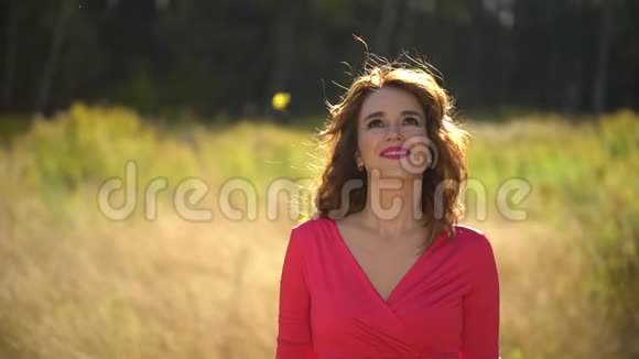 一幅美丽的女孩穿着红色连衣裙在森林里留着健康的长发秋天阳光明媚的秋天幸福的女人的脸视频的预览图