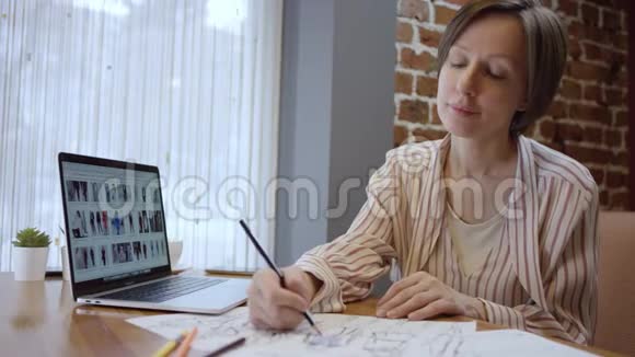 近距离拍摄创意时尚设计师的休闲服装查看笔记本电脑和绘制草图两个女人视频的预览图