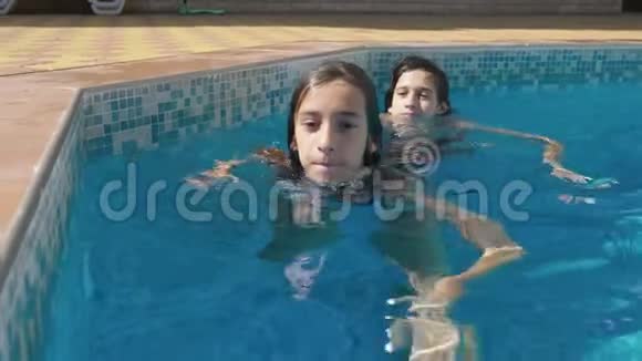 两个快乐的青少年一个兄妹正在游泳池里游泳慢动作稳定射击4k视频的预览图