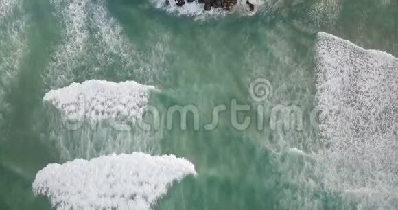 从空中俯瞰白色泡沫海浪抵达海岸热带岛屿棕榈树和度假屋视频的预览图