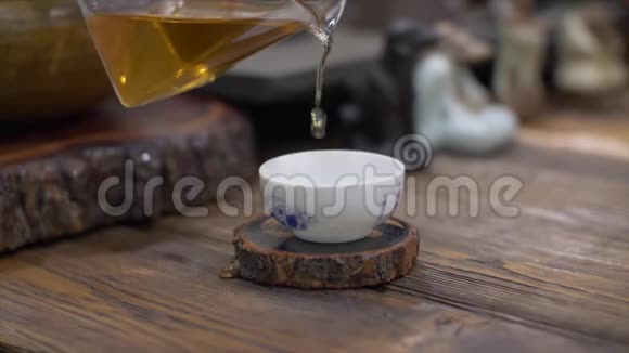 将冲泡好的绿茶倒入白陶瓷杯中从玻璃茶壶中慢慢倒入视频的预览图