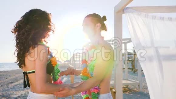 在异国度假胜地的海滩派对上男人和女人在热带岛屿的蜜月年轻夫妇背光阳光视频的预览图