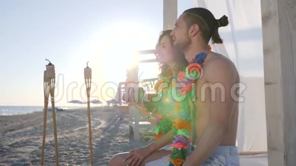 女人他的男人用手指着远处夏威夷的莱伊脖子上的年轻人在海边背光的阳光的光线视频的预览图