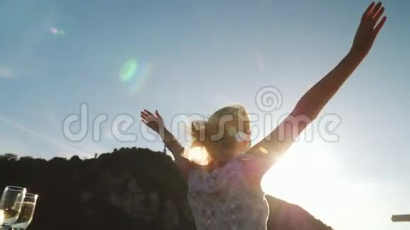 一个女人在船上享受游船伸出双手向太阳伸展跳舞视频的预览图