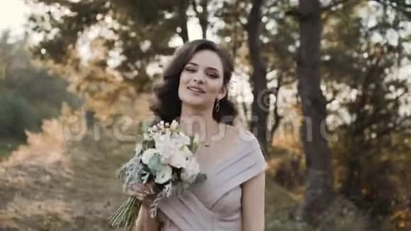一位美丽的新娘在公园的镜头前摆着结婚花束视频的预览图