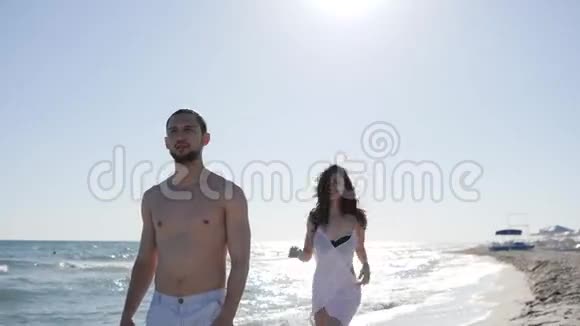 海滩上的朋友快乐的女孩在男人身上跳跃背对着背光度假时的爱情伴侣风吹起女人的头发视频的预览图