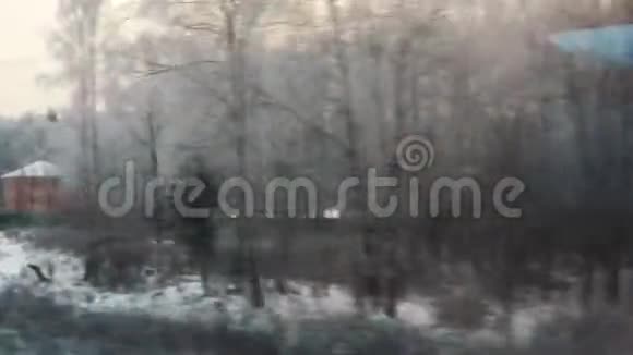火车从窗口观看冬季雪林村房屋在雪冬天的森林透过窗户视频的预览图