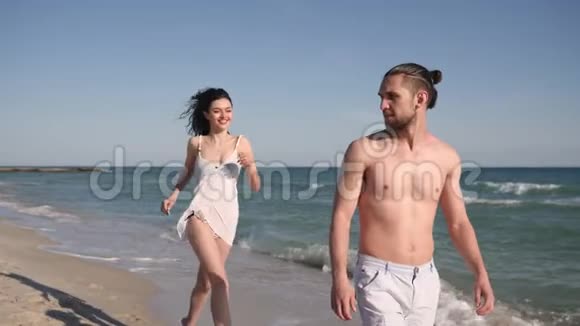 快乐的女孩跳在男人的背上在暑假爱一对夫妇风发热带沿着海洋海岸视频的预览图