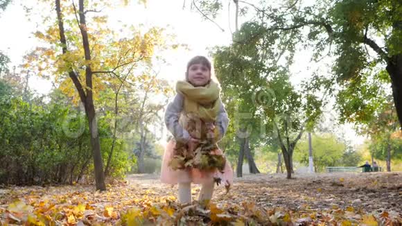 秋天户外背光的小女孩在公园里慢动作地扔黄叶视频的预览图