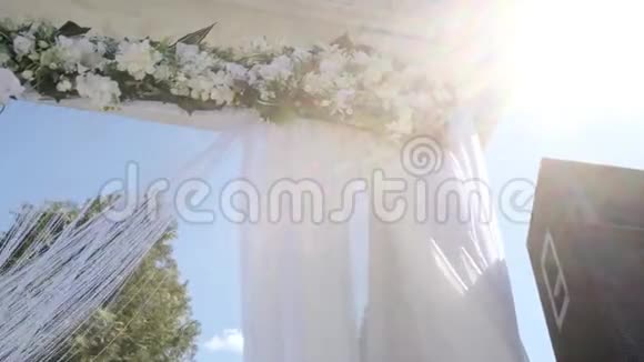 一个婚礼拱门装饰着鲜花和大型的风展织物在运动中射击视频的预览图