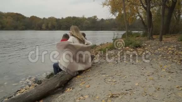 一家人坐在河边的原木上放松享受美丽的秋景视频的预览图