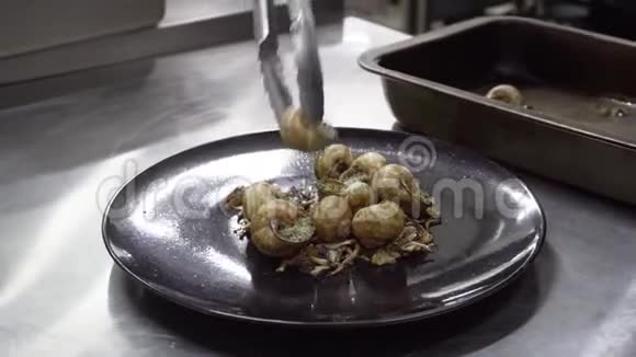 厨师把蜗牛放到盘子里在厨房准备美食视频的预览图