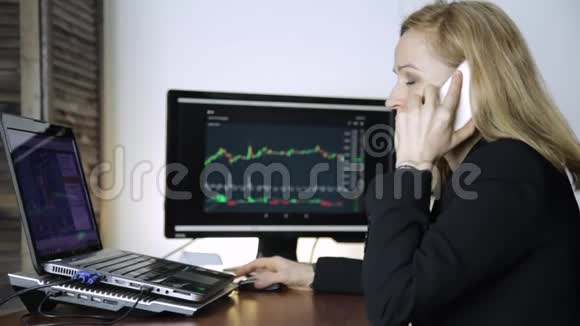 商务女士在电话上给客户提供建议并在电脑显示器上观看货币兑换图表做一个密码视频的预览图