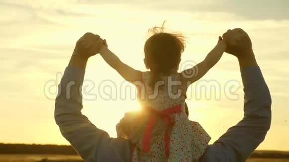 傍晚日落时一个带着父母的婴儿散步慢动作父亲带着他的女儿在他的肩膀上散步视频的预览图