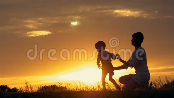 一个快乐的小男孩的剪影跑进他慈爱的母亲的怀里在夕阳面前拥抱视频的预览图