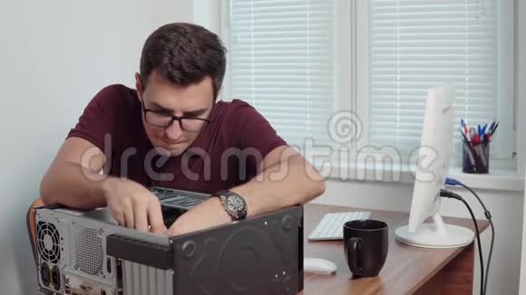 年轻的专业工人用螺丝刀修理办公室里的一台坏电脑并升级电脑硬件视频的预览图