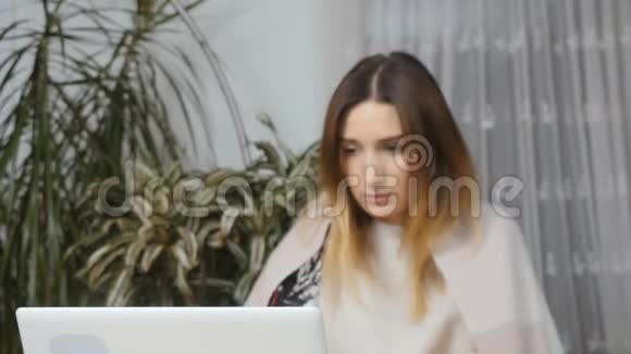 年轻生病的女孩在家拿着笔记本电脑工作咳嗽视频的预览图