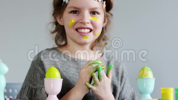 可爱的小女孩画着五颜六色的复活节彩蛋她弄脏了她的手和脸视频的预览图