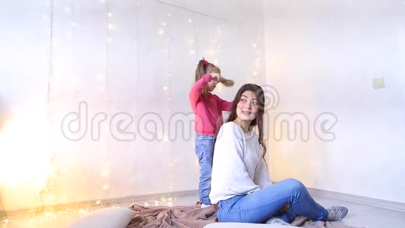 美丽的黑发女人坐在地板上小女儿拉着妈妈头发视频的预览图