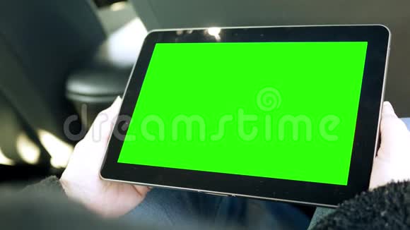 在汽车后座看绿色屏幕平板的女人视频的预览图