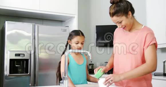 妈妈教女儿在厨房洗瓷器视频的预览图