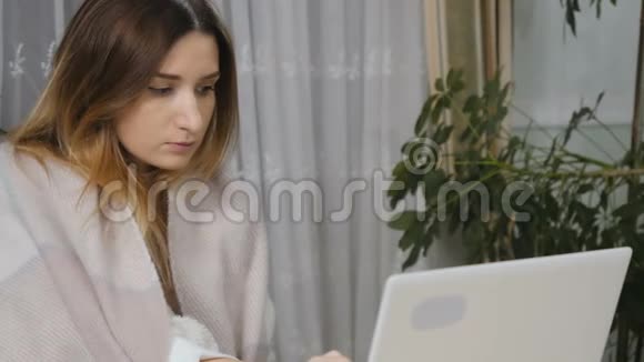 年轻的生病的女孩在家拿着笔记本电脑工作视频的预览图