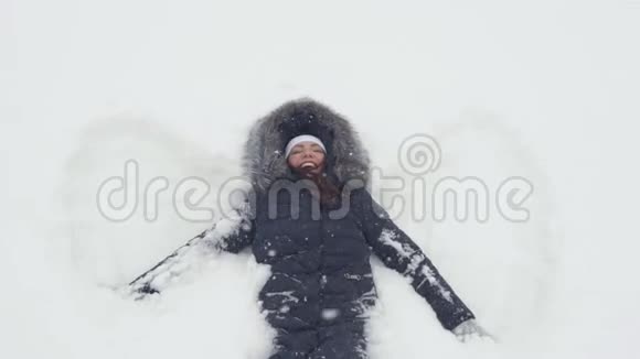 快乐的女孩躺在雪地上展示天使视频的预览图