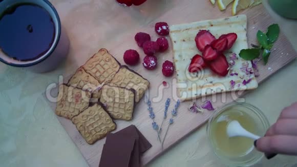 将蜂蜜与饼干巧克力覆盆子和草莓混合在桌上视频的预览图