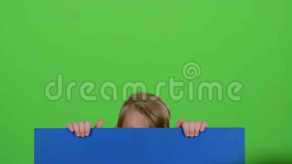 小男孩从一张蓝色海报后面出现看着他再次躲藏起来绿色屏幕视频的预览图