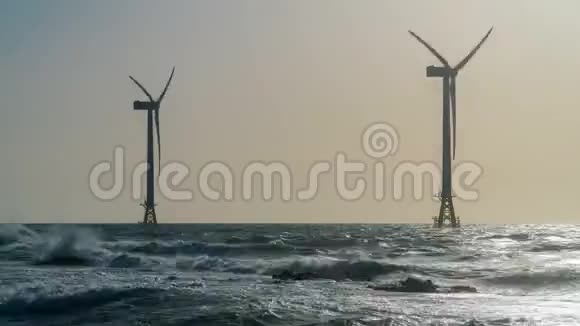 日落时海中的时移风车风力发电机的剪影视频的预览图
