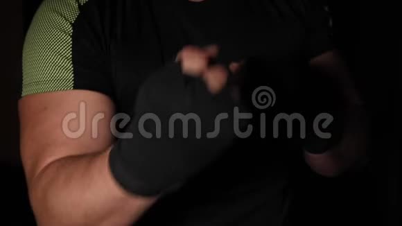 运动员站在拳击架上双手用黑色绷带包扎视频的预览图