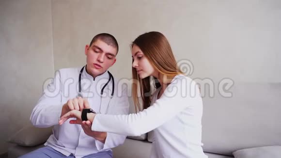 医生画像向病人解释如何使用智能手表监测他们的健康并坐在医院的沙发上视频的预览图
