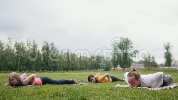 三位年轻模特运动员在公园里练习瑜伽视频的预览图