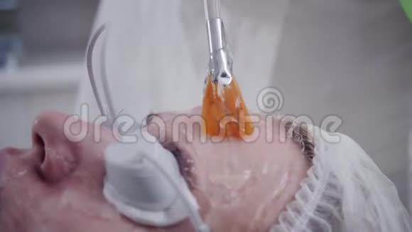 医生给病人涂上一种特殊的凝胶用专业设备抗痘光疗美丽的女人视频的预览图