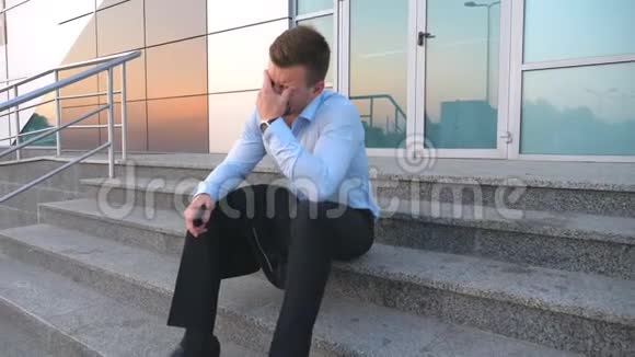 坐在办公楼附近的楼梯上哭得心烦意乱的经理一个绝望的年轻商人视频的预览图