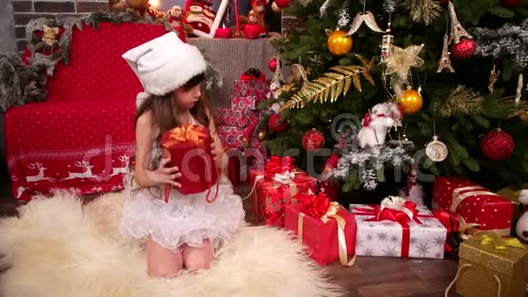 穿着新年服装的女孩在圣诞树旁带着新年惊喜给妹妹圣诞假期快乐视频的预览图