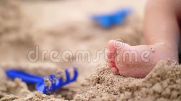 柔软的焦点一个小宝宝脚踩在沙滩上的特写镜头附近有玩具视频的预览图