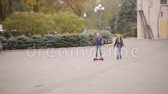 两个女朋友青少年玩得很开心女孩驾驶着公园里的电子陀螺仪视频的预览图