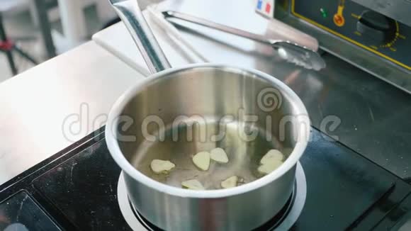 厨师手戴手套将豌豆放入锅中放入切碎的大蒜视频的预览图