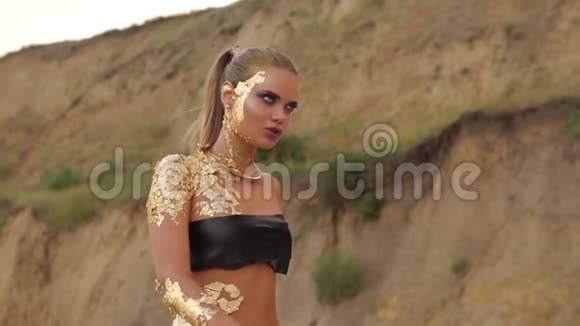 迷人的模特金色的皮肤和穿在她的腹部和专业的化妆走在海滩上年轻的金发女郎视频的预览图