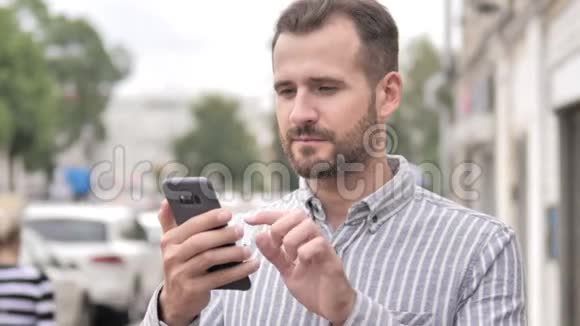 户外胡子休闲男子使用智能手机视频的预览图