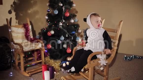 在圣诞树和蜡烛的背景下孩子在摇椅上摇摆圣诞节的气氛视频的预览图