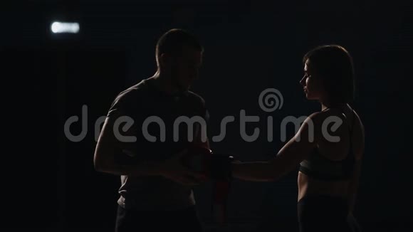 教练在战斗前给拳击手的女孩戴上拳击手套为比赛做准备视频的预览图