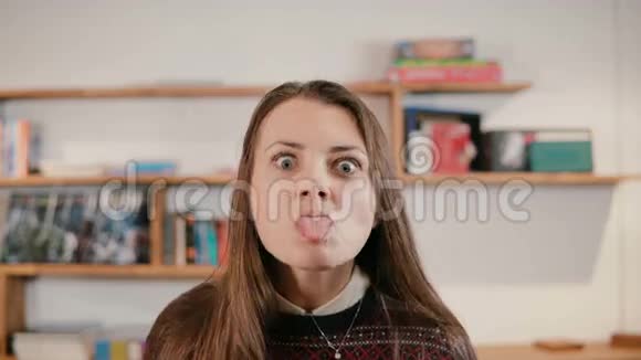 年轻女人的肖像做傻脸伸出舌头女孩嚼口香糖笑现代办公室的雇员视频的预览图