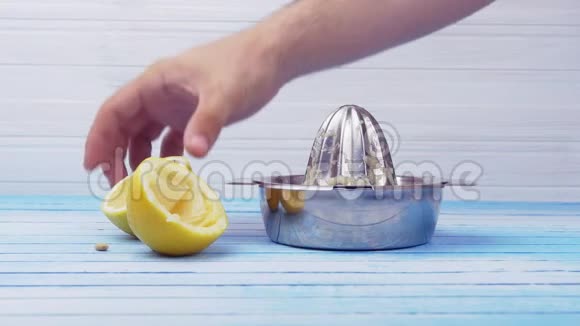 手捏新鲜有机生物柠檬与闪亮不锈钢榨汁机视频的预览图