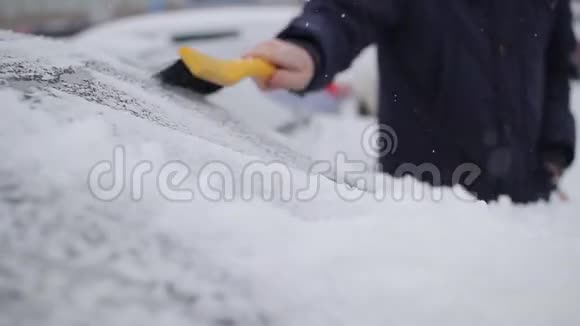 人用刷子把车从雪中擦干净视频的预览图